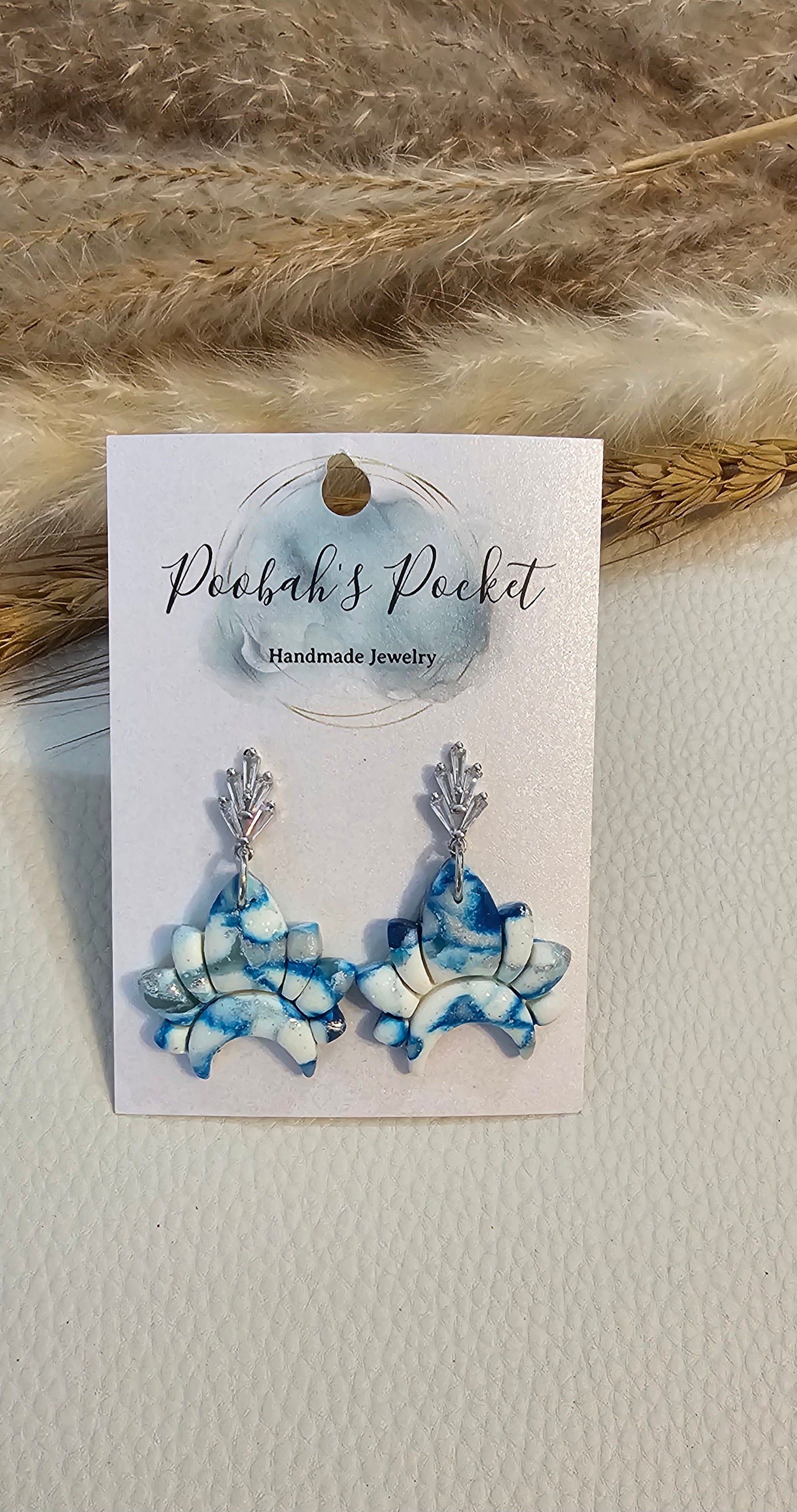 crown shape polymer clay earrings with hues of blue and white.
